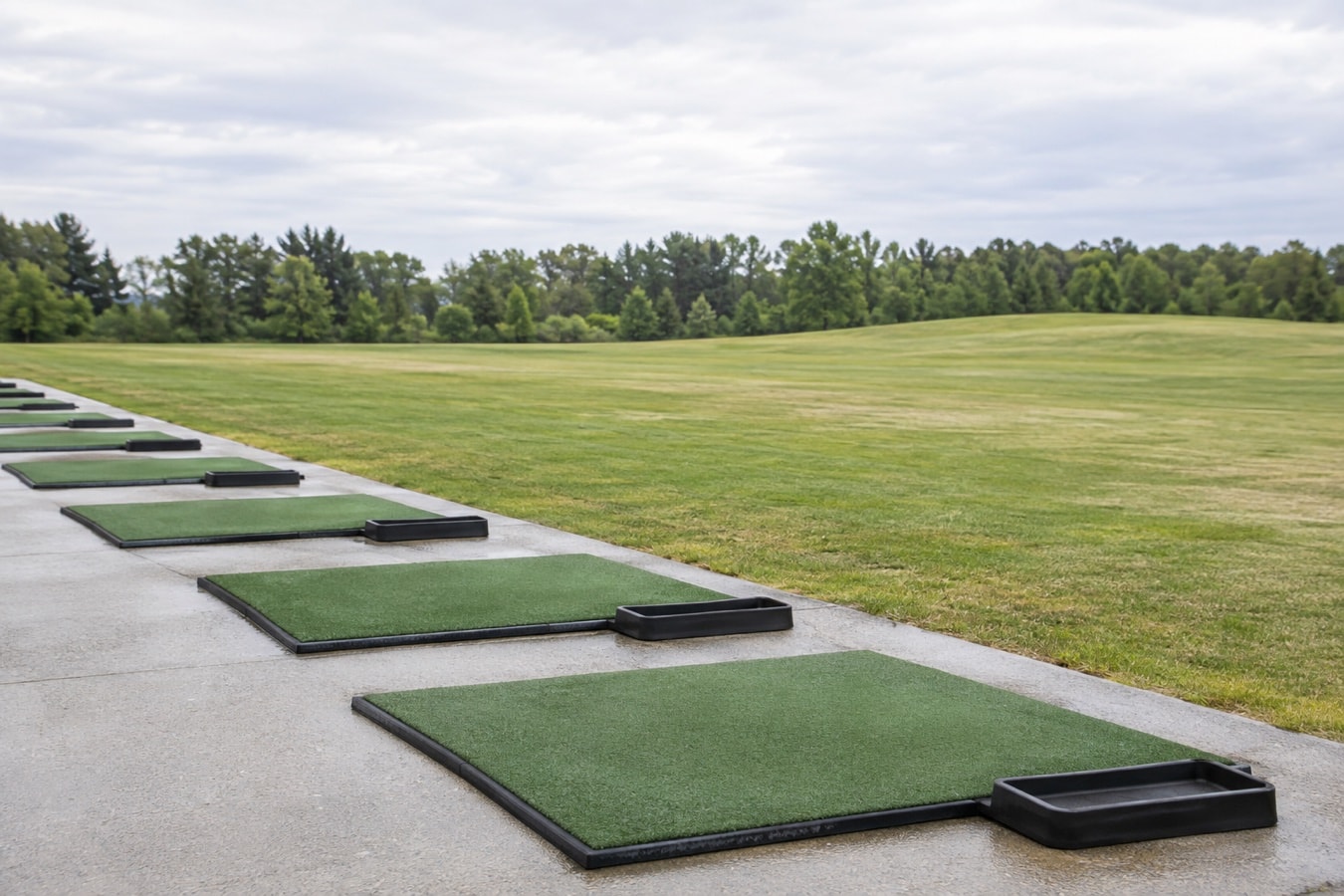 A row of empty practice mats beside open grass