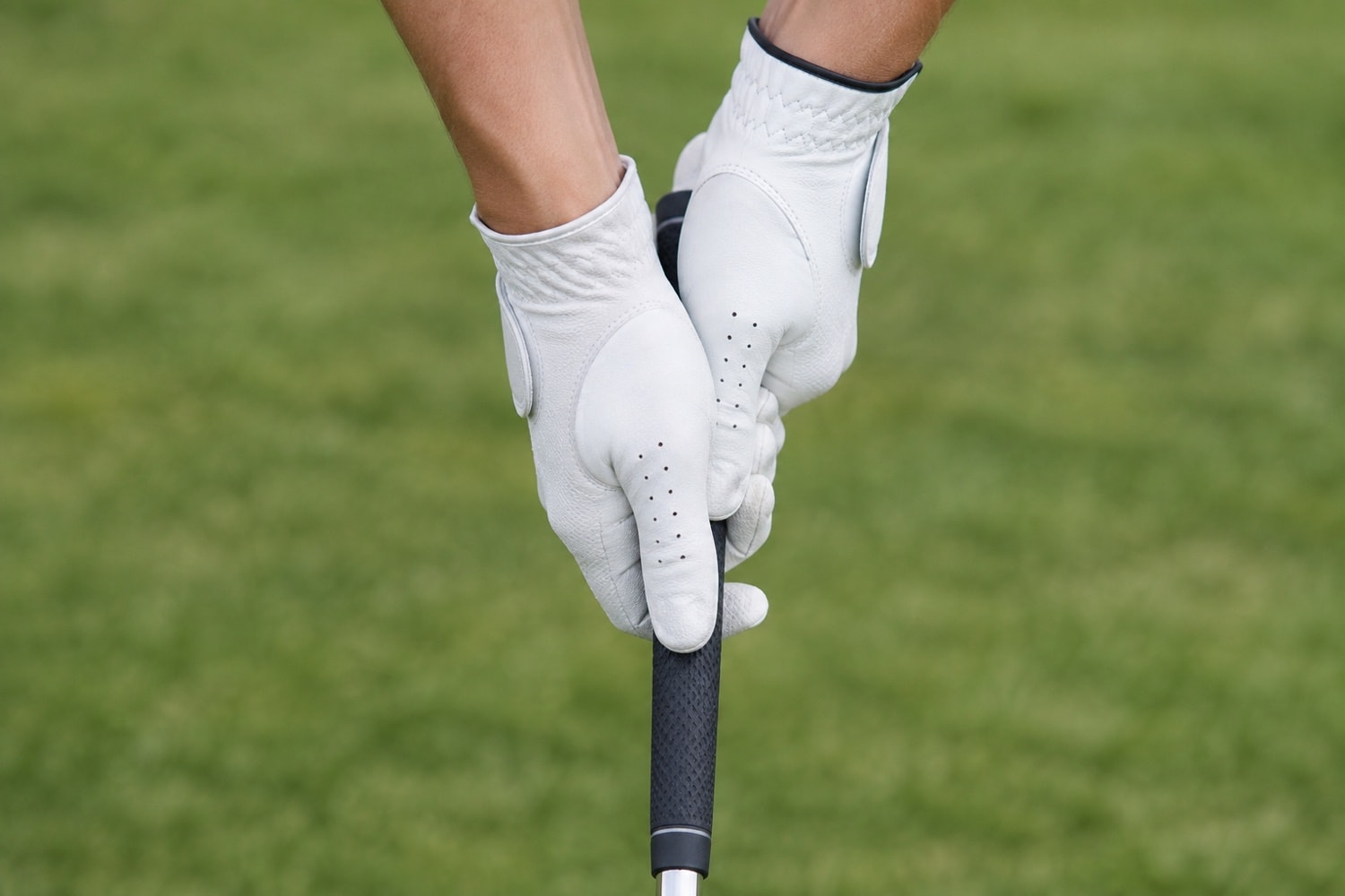 Gloved hands resting on a plain golf club grip