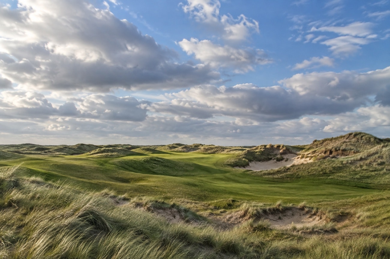 Rolling grass-covered links dunes beneath a broad sky